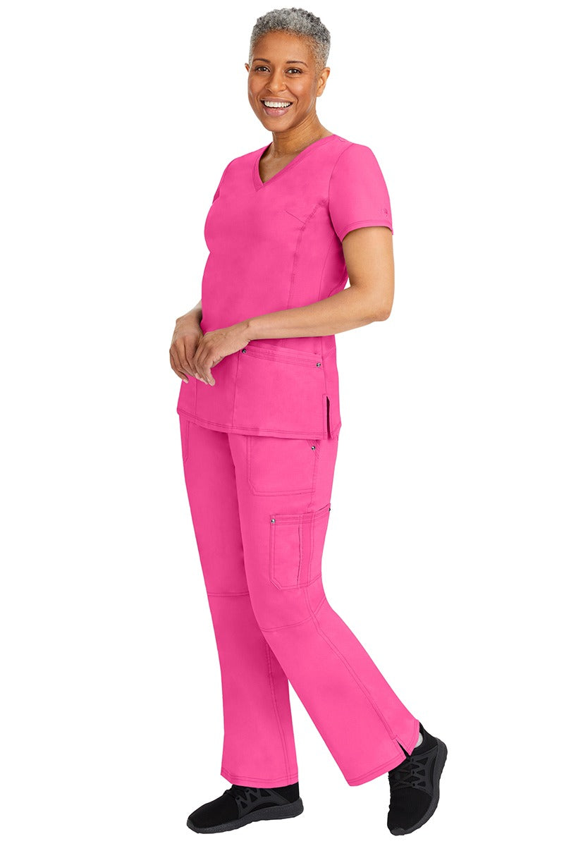 A young female nurse wearing a pair of Purple Label Women's Tori Yoga Waistband Scrub Pants from Healing Hands in Shocking Pink featuring a modern fit.