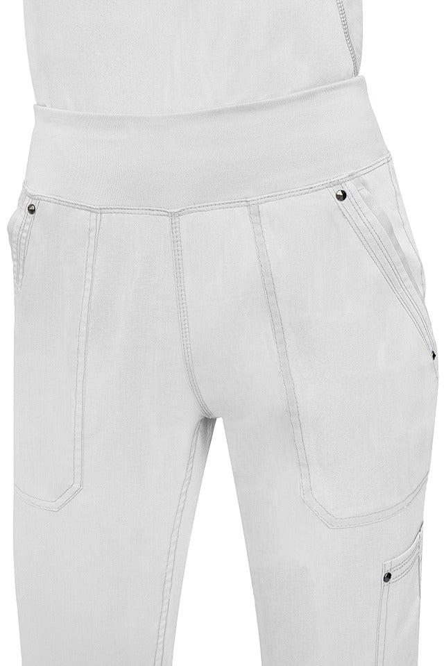 A young female healthcare professional wearing a Purple Label Women's Tori Yoga Waistband Scrub Pant in White featuring a unique fabric that resists wrinkles, shrinking, & fading better than traditional cotton scrubs.