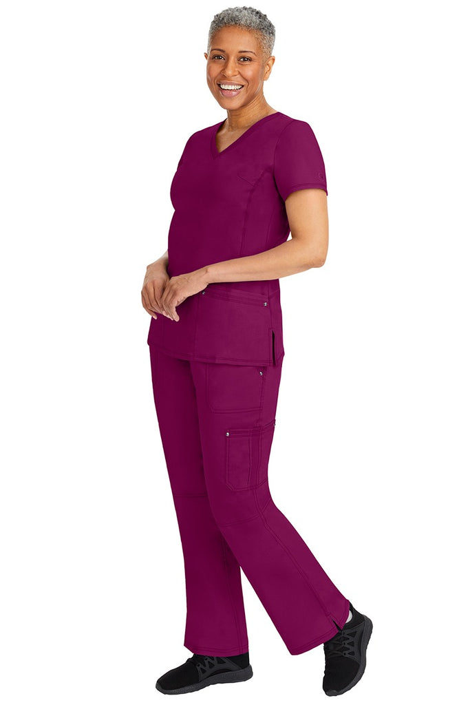 A young female nurse wearing a pair of Purple Label Women's Tori Yoga Waistband Scrub Pants from Healing Hands in Wine featuring a modern fit.