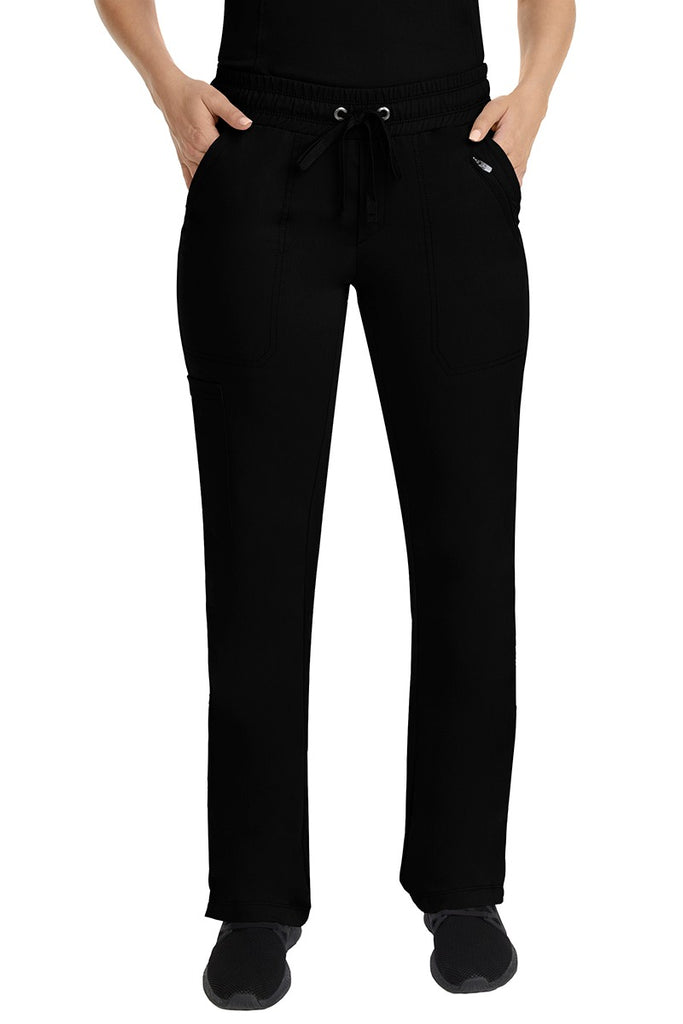A young female Nurse Practitioner wearing a Purple Label Women's Tanya Drawstring Cargo Scrub Pant in Black featuring a fully elasticized comfort stretch waistband.