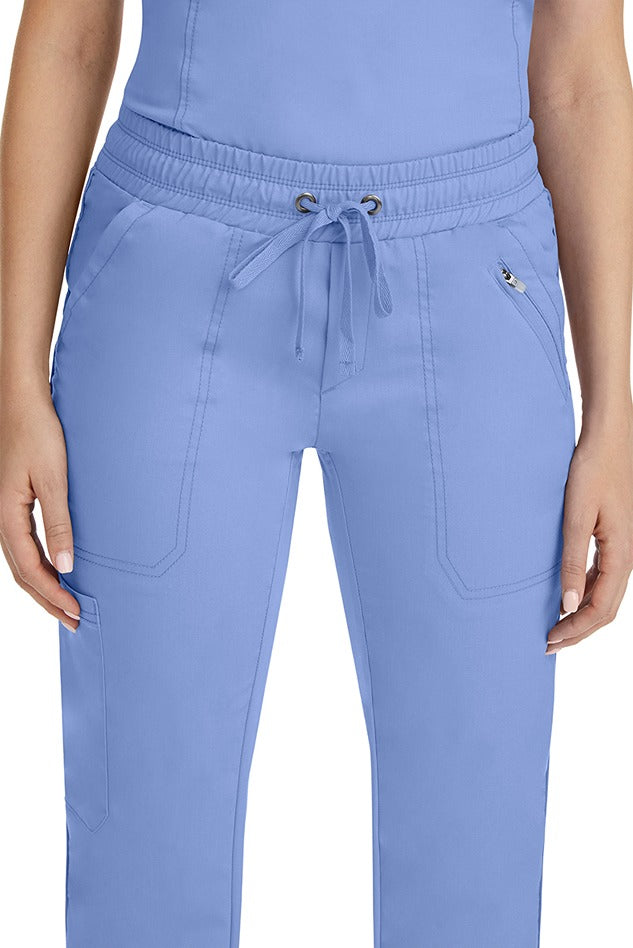 A close up view of a female nurse wearing a Purple Label Women's Tanya Drawstring Cargo Scrub Pant in Ceil featuring a front zipper pocket located on the wearer's left side.