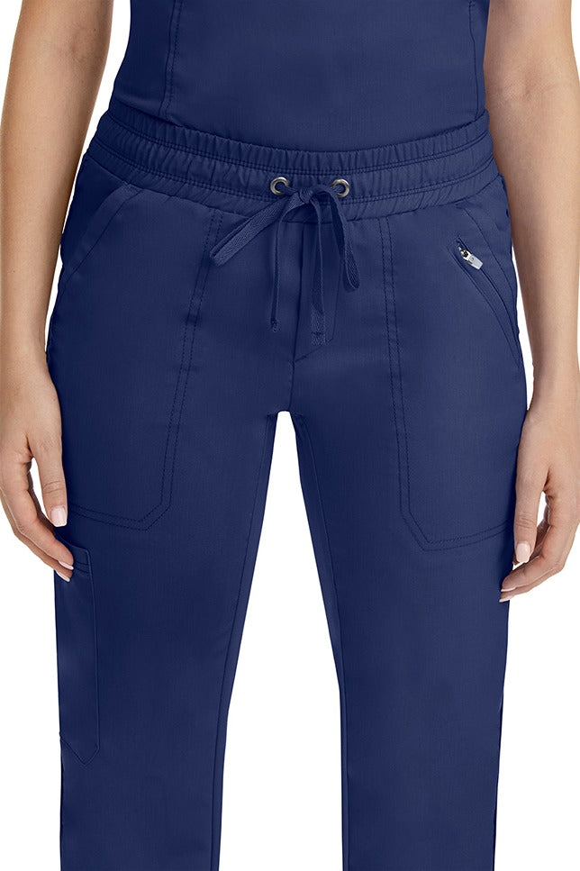 A close up view of a female nurse wearing a Purple Label Women's Tanya Drawstring Cargo Scrub Pant in Navy featuring a front zipper pocket located on the wearer's left side.
