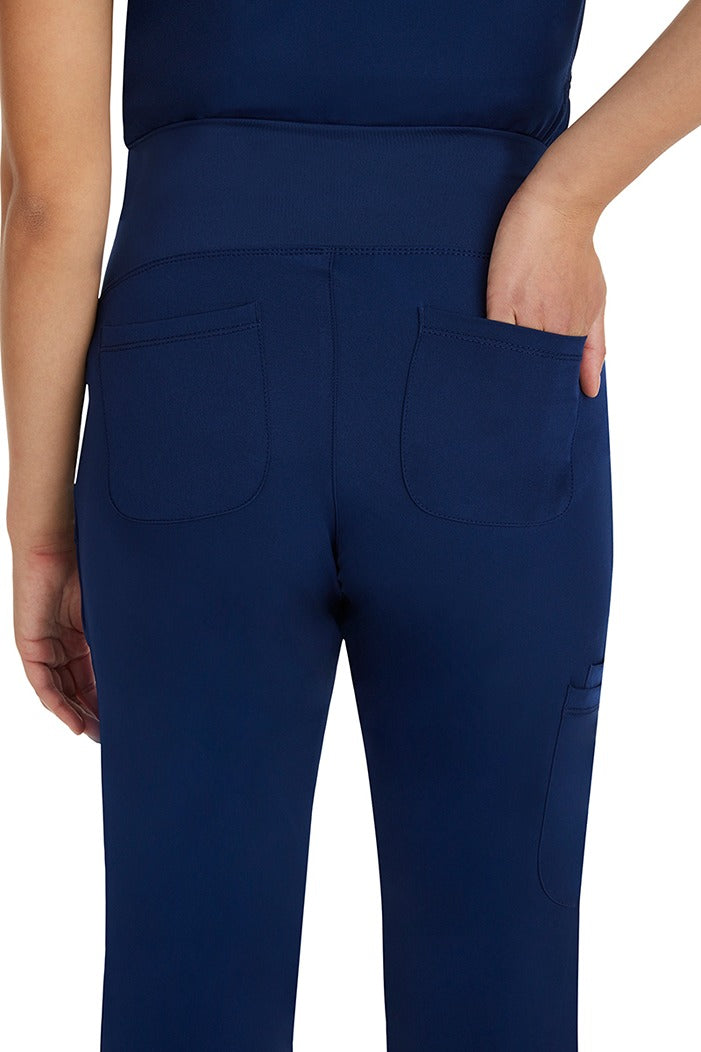 A young female nurse wearing a pair of HH-Works Women's Rose Maternity Women's Scrub Pants in Navy size XS featuring two back pockets and an elastic yoga waistband.