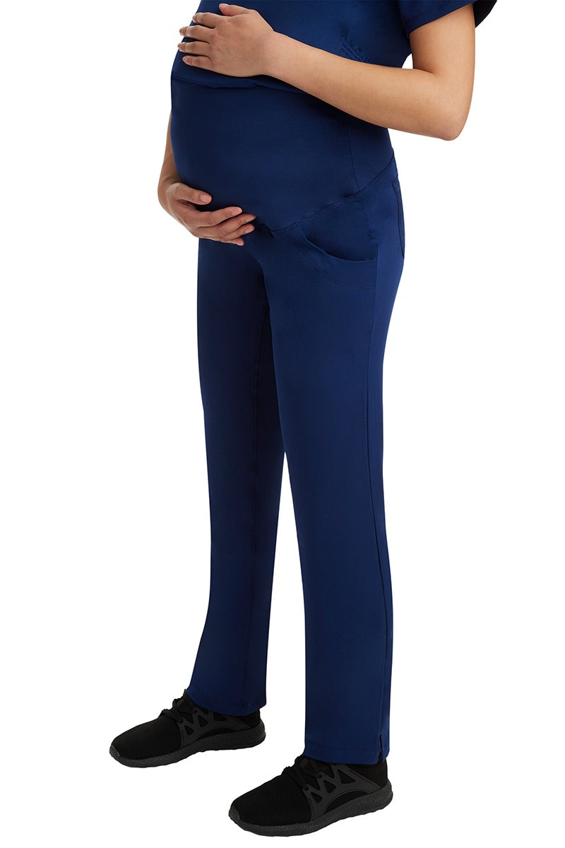 A young woman wearing an HH-Works Women's Rose Maternity Cargo Scrub Pant in Navy featuring two side pockets and a double sided pocket for all of your on the hob storage needs.