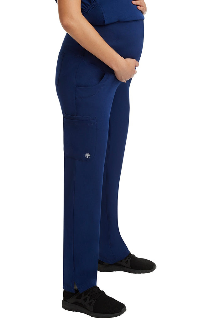 A female Home Care Registered Nurse wearing an HH-Works Women's Rose Maternity Cargo Scrub Pant in Navy featuring side slits for additional mobility.