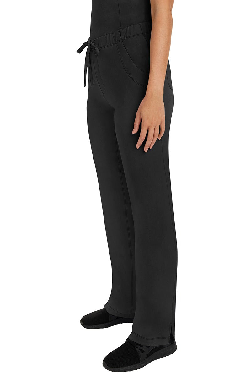 A woman Home Care Registered Nurse wearing a pair of HH-Works Women's Rebecca Multi-Pocket Drawstring Pants in Black featuring side slits for additional range of motion.