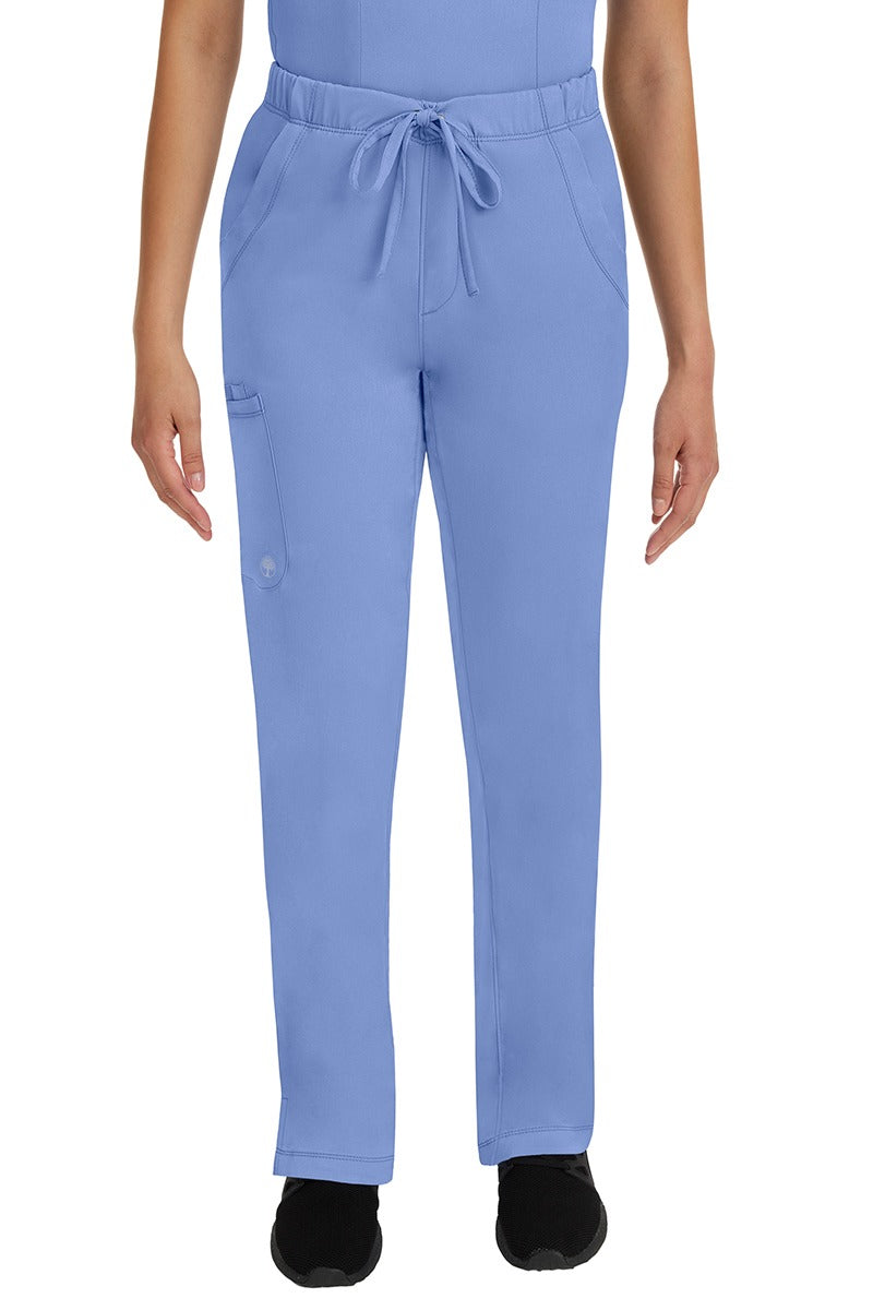 A young lady LPN wearing an HH Works Women's Rebecca Multi-Pocket Drawstring Pant in Ceil featuring n all elastic waistband with a drawstring tie front.