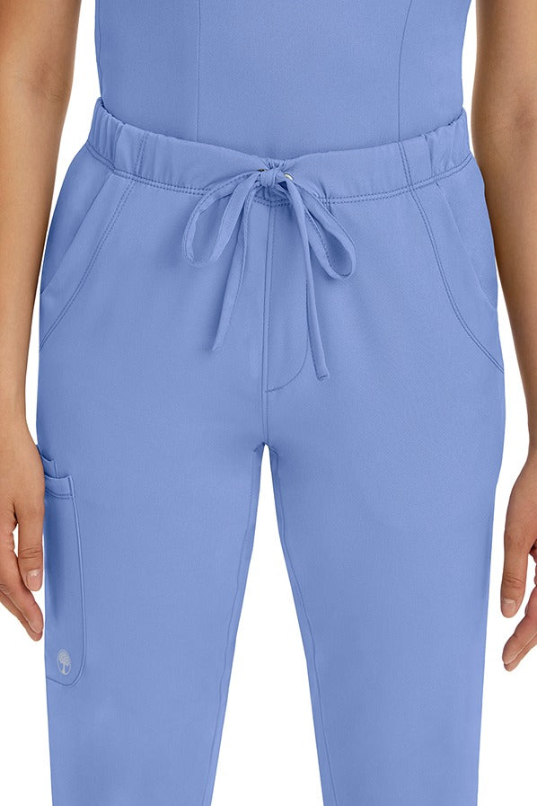 A female LPN wearing a pair of HH-Works Women's Rebecca Multi-Pocket Drawstring Pants in Ceil featuring 2 front slip pockets with a cargo pocket at the wearer's right leg.