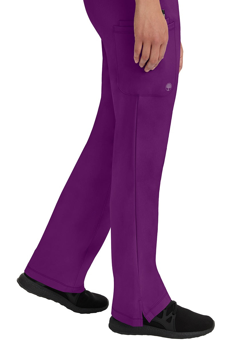 A young woman wearing an HH-Works Women's Rebecca Multi-Pocket Drawstring Pant in Eggplant. Perfect for Healthcare Professionals working in Hospitals or as Physical Therapists, Optometrists, & Chiropractors!