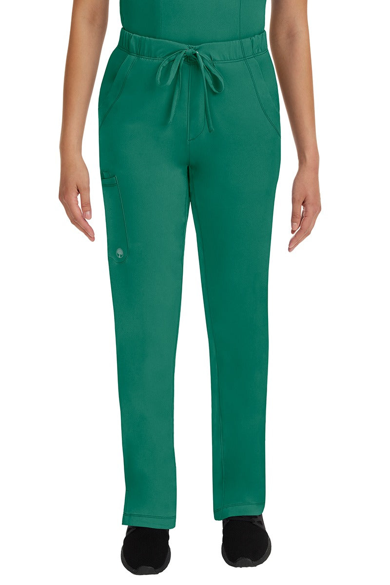 A young lady LPN wearing an HH Works Women's Rebecca Multi-Pocket Drawstring Pant in Hunter Green featuring n all elastic waistband with a drawstring tie front.