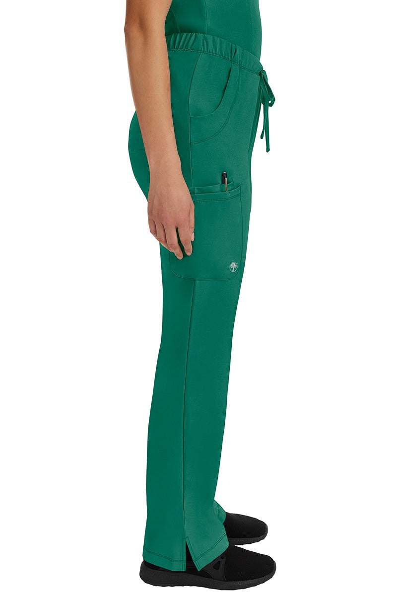 A young woman wearing an HH-Works Women's Rebecca Multi-Pocket Drawstring Pant in Hunter Green featuring a super comfortable stretch fabric made of 91% polyester & 9% spandex.