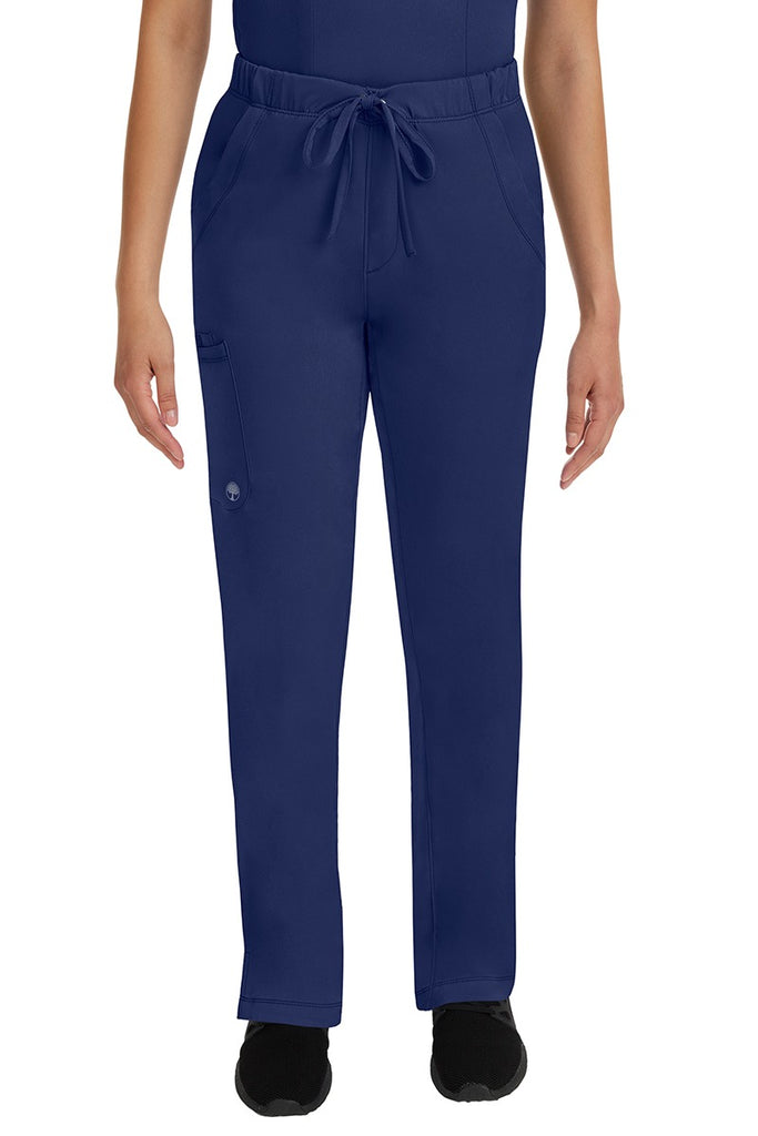 A young lady LPN wearing an HH Works Women's Rebecca Multi-Pocket Drawstring Pant in Navy featuring n all elastic waistband with a drawstring tie front.