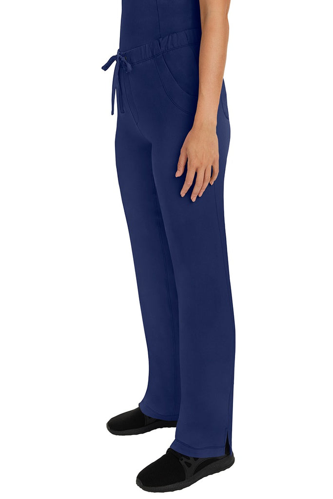 A woman Home Care Registered Nurse wearing a pair of HH-Works Women's Rebecca Multi-Pocket Drawstring Pants in Navy featuring side slits for additional range of motion.