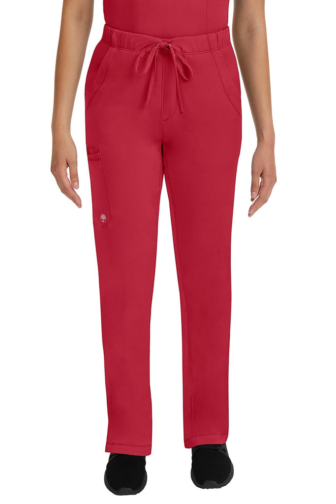 A young lady LPN wearing an HH Works Women's Rebecca Multi-Pocket Drawstring Pant in Red featuring n all elastic waistband with a drawstring tie front.