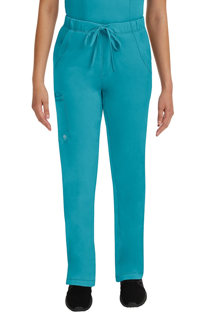 A young lady LPN wearing an HH Works Women's Rebecca Multi-Pocket Drawstring Pant in Teal featuring n all elastic waistband with a drawstring tie front.