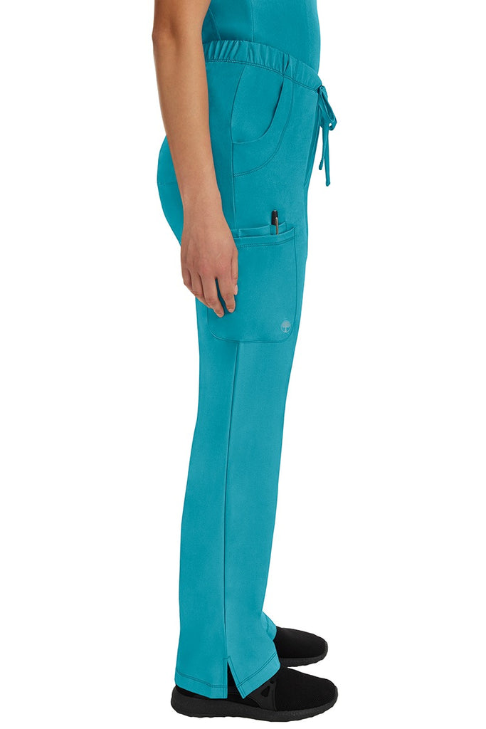 A young woman wearing an HH-Works Women's Rebecca Multi-Pocket Drawstring Pant in Teal featuring a super comfortable stretch fabric made of 91% polyester & 9% spandex.