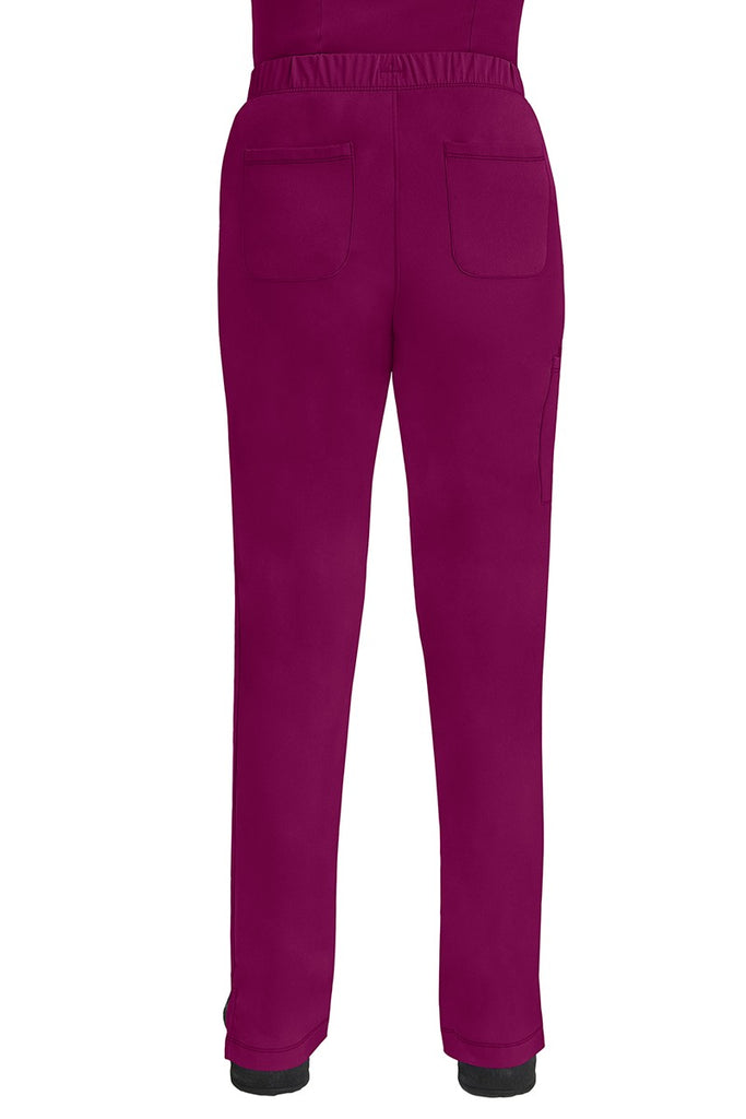 A lady CNA wearing an HH-Works Women's Rebecca Multi-Pocket Drawstring Pant in Wine featuring 2 back patch pockets for any additional on the job storage needs.