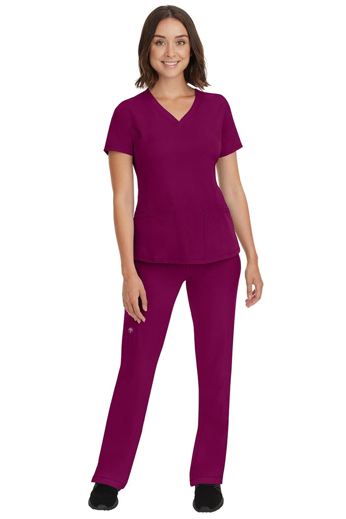 A young female nurse wearing a Women's Rebecca Multi-Pocket Drawstring Pant from HH Works in Wine featuring a quick-dry, moisture wicking fabric that is fade resistant.