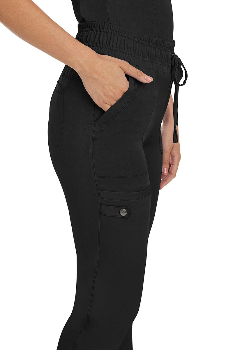 A female nurse wearing a pair of the HH Works Women's Renee Jogger Scrub Pants in Black featuring a total of 6 pockets for all of your on the go storage needs.