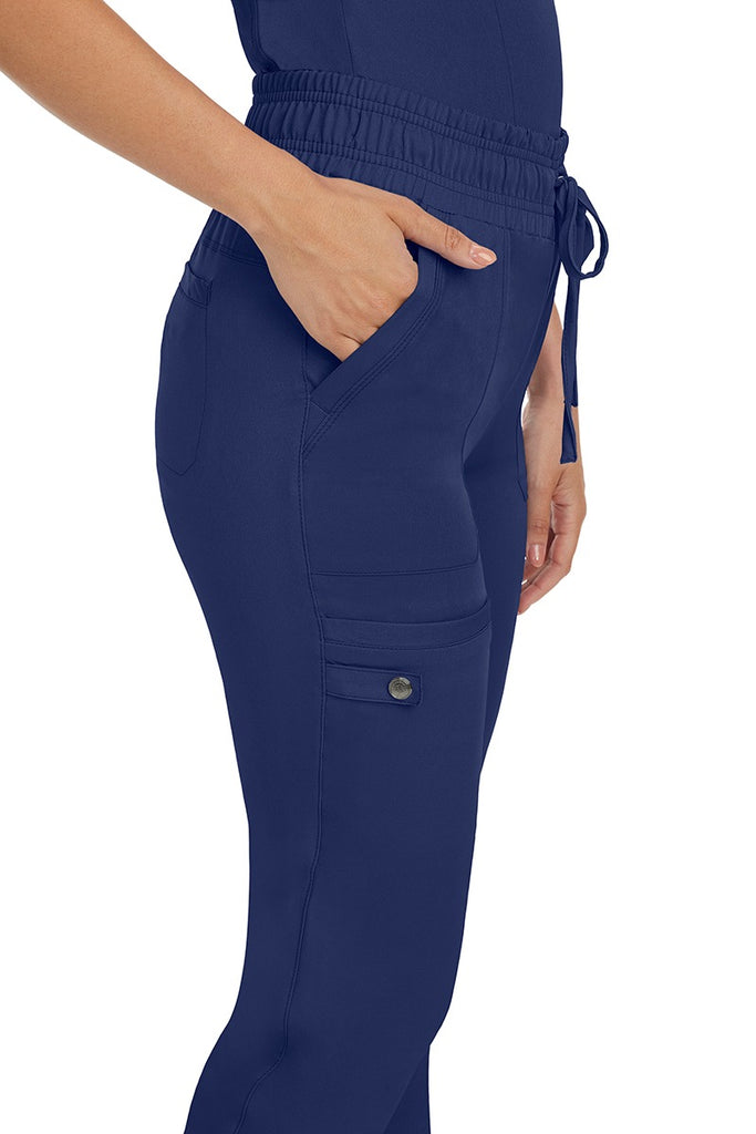 A female nurse wearing a pair of the HH Works Women's Renee Jogger Scrub Pants in Navy featuring a total of 6 pockets for all of your on the go storage needs.