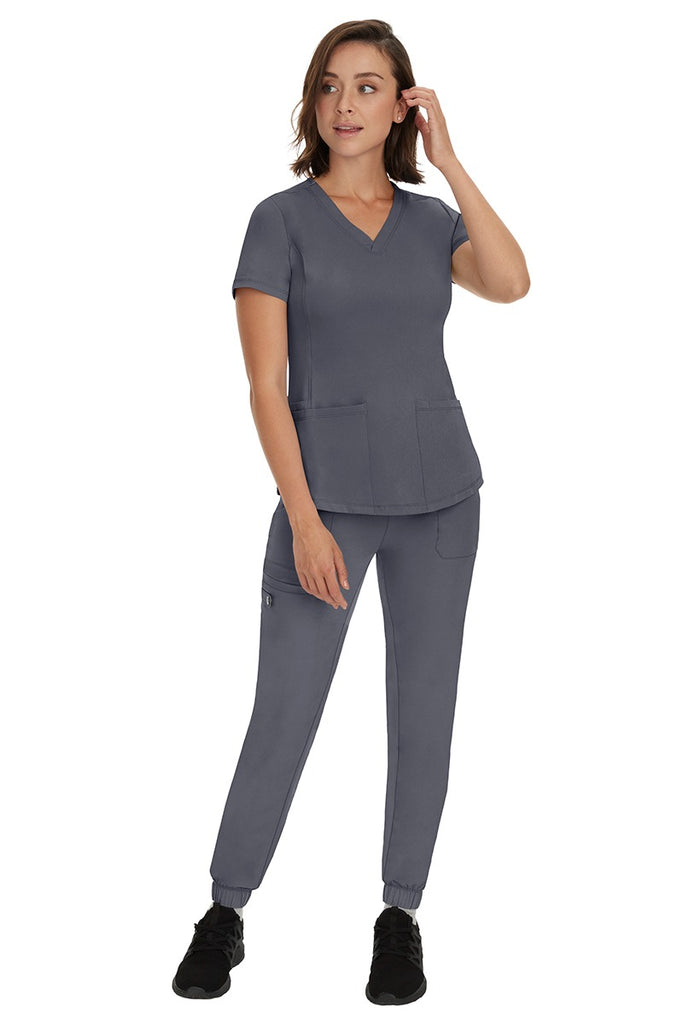 A young female RN wearing an HH Works Women's Renee Jogger Scrub Pant in Pewter featuring a modern fit with an elastic waist.