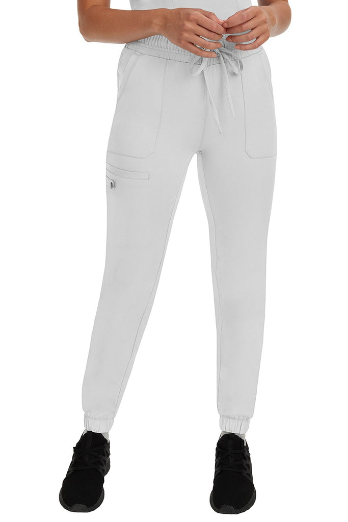 A young woman LVN wearing a pair of the HH Works Women's Renee Jogger Scrub Pants in White featuring a super comfortable, easy care fabric.