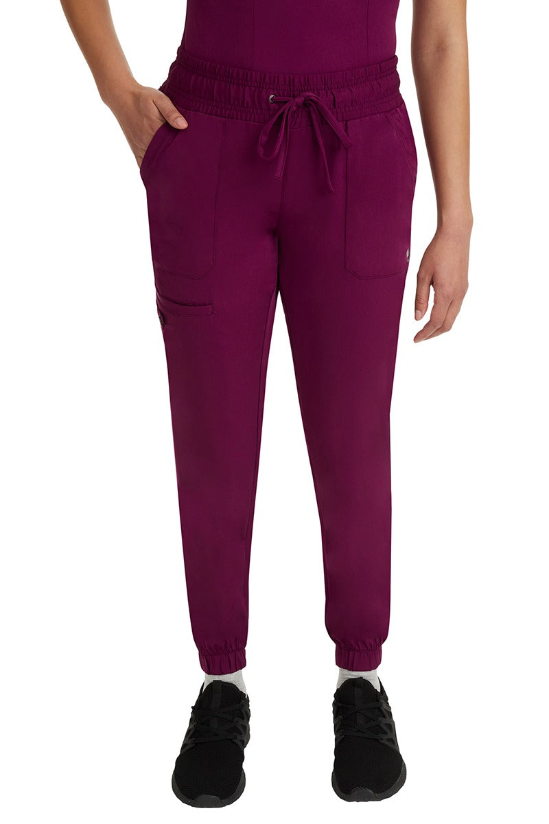 A young woman LVN wearing a pair of the HH Works Women's Renee Jogger Scrub Pants in Wine featuring a super comfortable, easy care fabric.