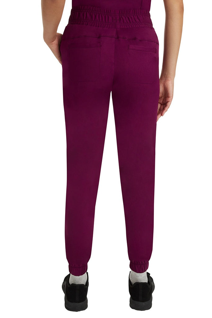 A young Home Care Registered Nurse wearing a Women's Renee Jogger Scrub Pant from HH Works in Wine featuring 2 back patch pockets for additional storage room.