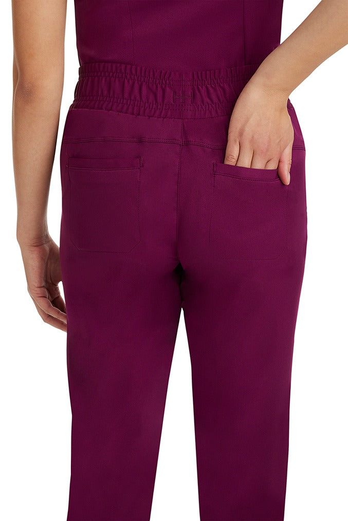 A female nurse wearing a Women's Renee Jogger Scrub Pant from HH Works in Wine featuring a drawstring tie front.