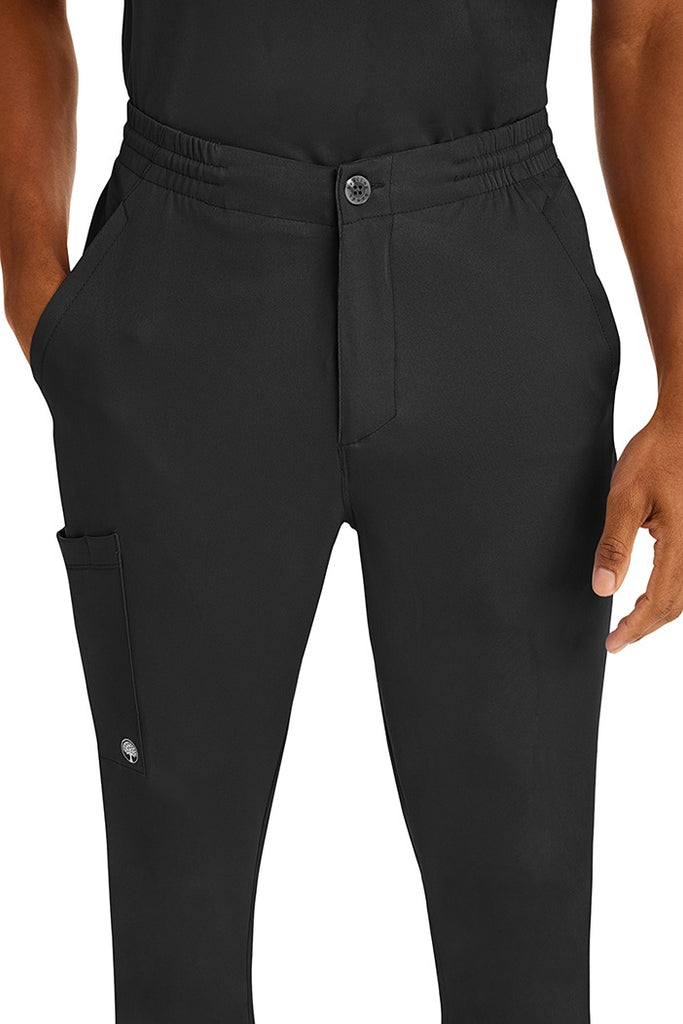 A young man wearing a Men's Ryan Multi-Pocket Cargo Scrub Pant from HH Works in Black featuring a super comfortable stretch fabric made of 91% polyester & 9% spandex.