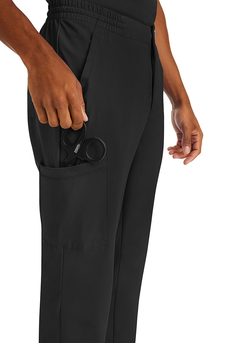 A male nurse wearing an HH-Works Men's Ryan Multi-Pocket Cargo Scrub Pant in Black featuring a total of 6 pockets for all of your on the job storage needs.