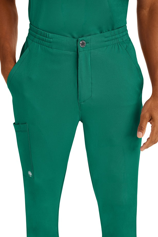 A young man wearing a Men's Ryan Multi-Pocket Cargo Scrub Pant from HH Works in Hunter Green featuring a super comfortable stretch fabric made of 91% polyester & 9% spandex.