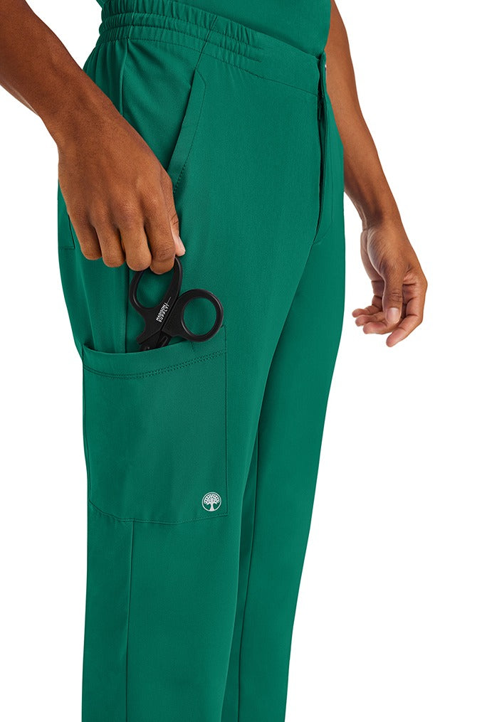 A male nurse wearing an HH-Works Men's Ryan Multi-Pocket Cargo Scrub Pant in Hunter Green featuring a total of 6 pockets for all of your on the job storage needs.