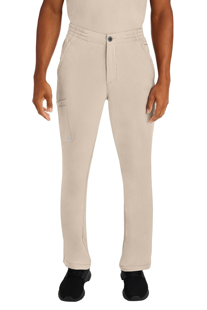 A male LPN wearing a Men's Ryan Multi-Pocket Cargo Scrub Pant from HH Works in Khaki size large. featuring a functional zipper front with button closure.