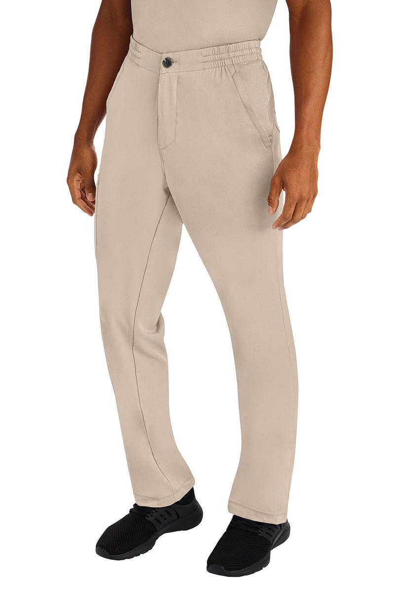 A male clinical nurse specialist wearing an HH-Works Men's Ryan Multi-Pocket Cargo Scrub Pant in Khaki featuring a hidden drawstring & elastic waistband.