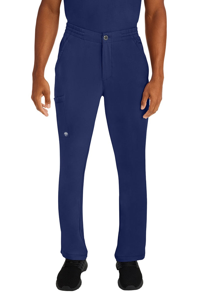 A male LPN wearing a Men's Ryan Multi-Pocket Cargo Scrub Pant from HH Works in Navy size large. featuring a functional zipper front with button closure.