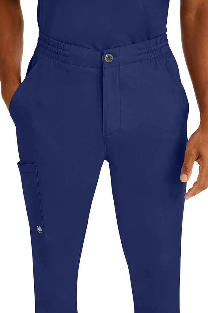 A young man wearing a Men's Ryan Multi-Pocket Cargo Scrub Pant from HH Works in Navy featuring a super comfortable stretch fabric made of 91% polyester & 9% spandex.