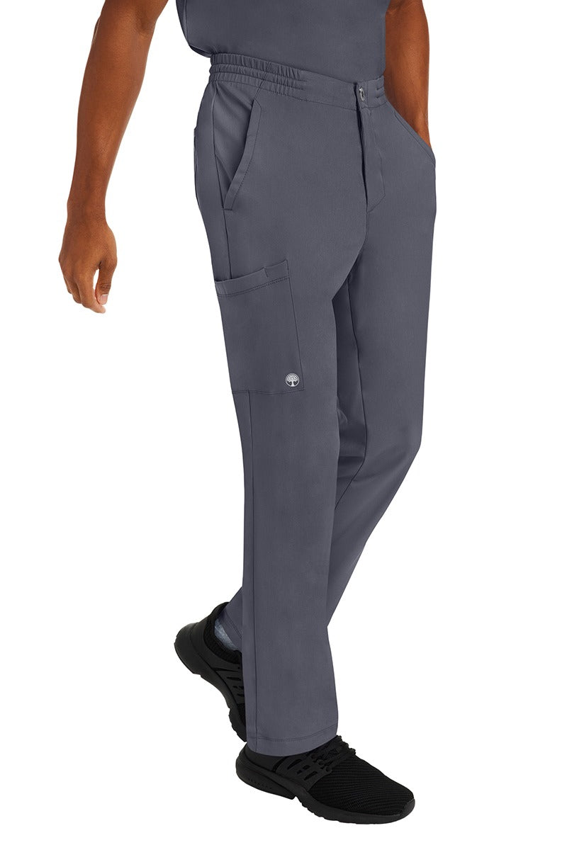A young male CNA wearing a pair of HH-Works Men's Ryan Multi-Pocket Cargo Scrub Pants in Pewter featuring two front patch pockets.
