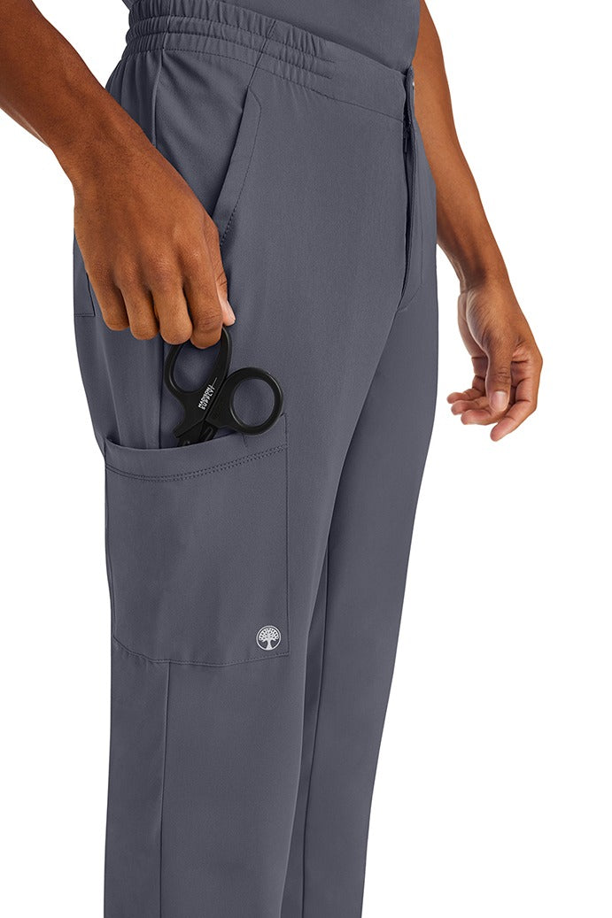 A male nurse wearing an HH-Works Men's Ryan Multi-Pocket Cargo Scrub Pant in Pewter featuring a total of 6 pockets for all of your on the job storage needs.