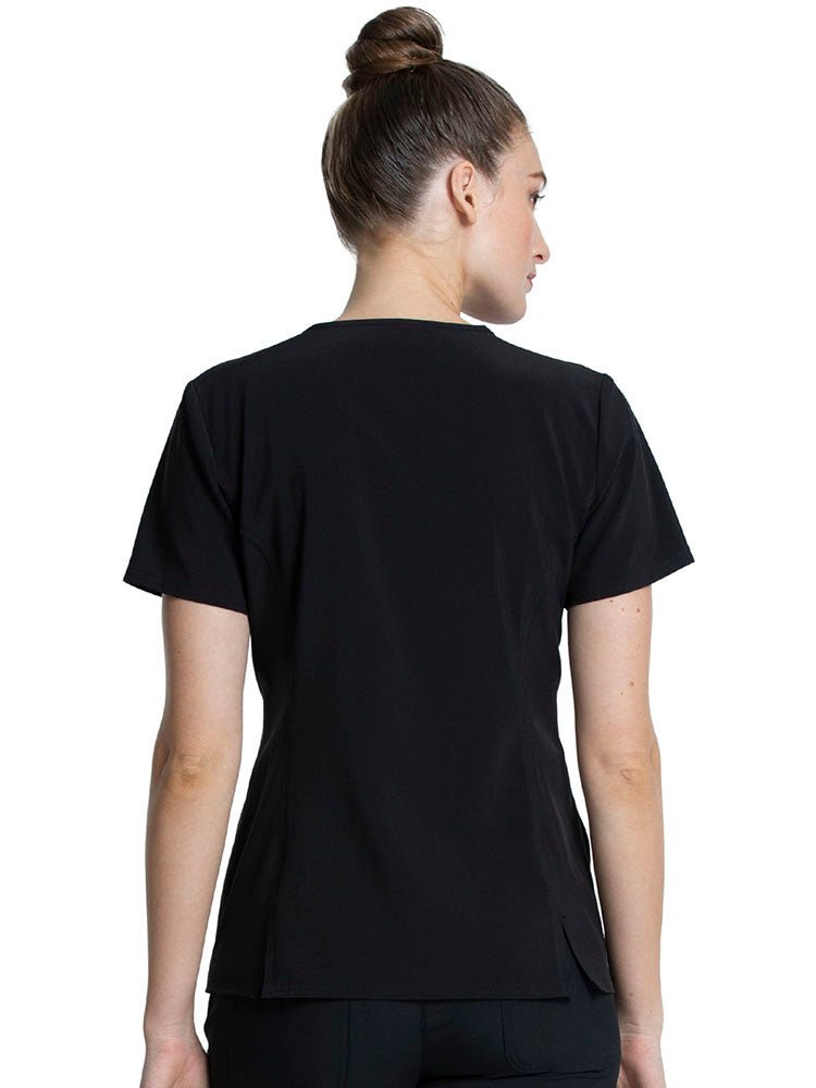 A young female LPN wearing a Tooniforms Women's V-neck Print Scrub Top from Cherokee in "Glass Slipper" size medium featuring a center back length of 25.5".
