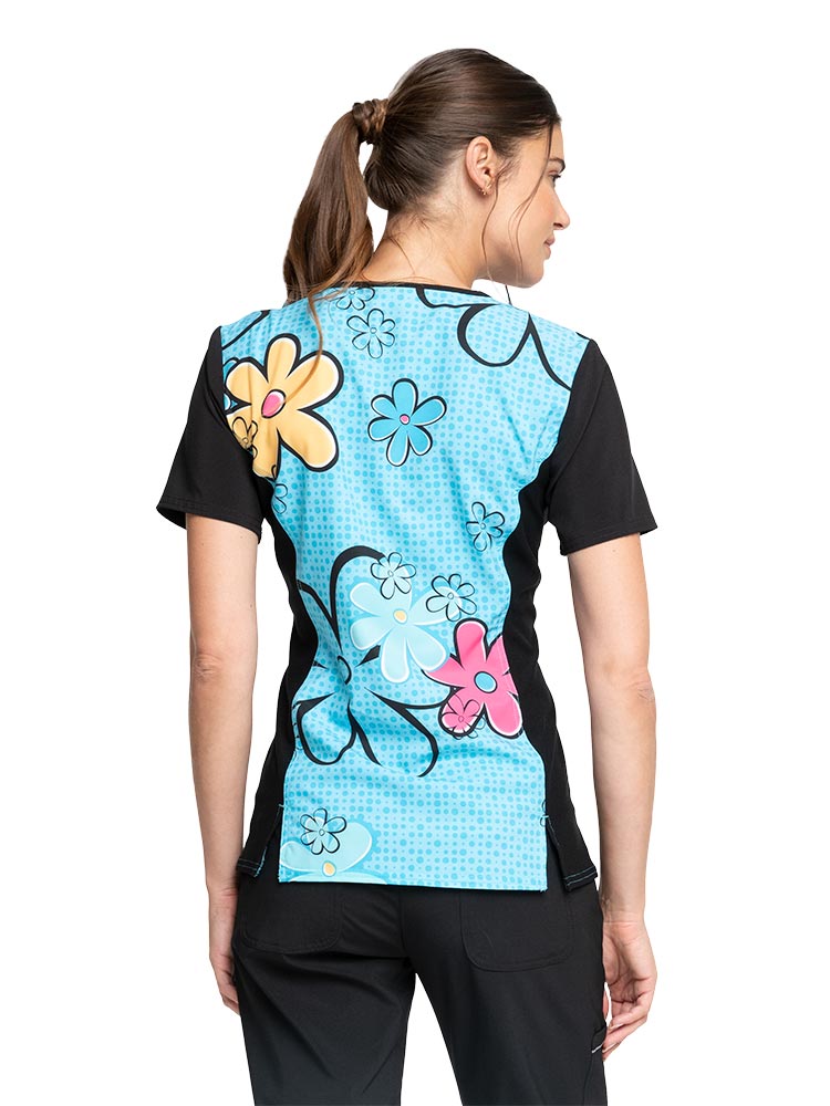 Young nurse wearing a "Scooby Sunshine" Tooniforms Women's V-Neck Print Scrub Top featuring a contrast neckband and sleeves plus contrast knit side panels.