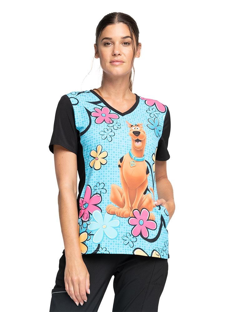 Young woman wearing a Women's V-Neck Print Scrub Top from Cherokee Tooniforms on "Scooby Sunshine".