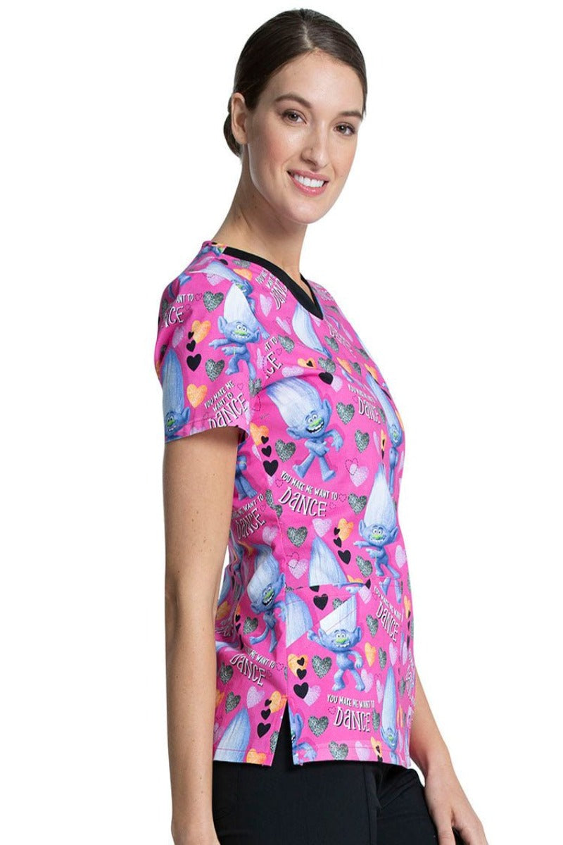 A young nurse wearing a Tooniforms Women's V-Neck Printed Scrub Top in "Diamond Dance" featuring side vents for additional mobility throughout the day.