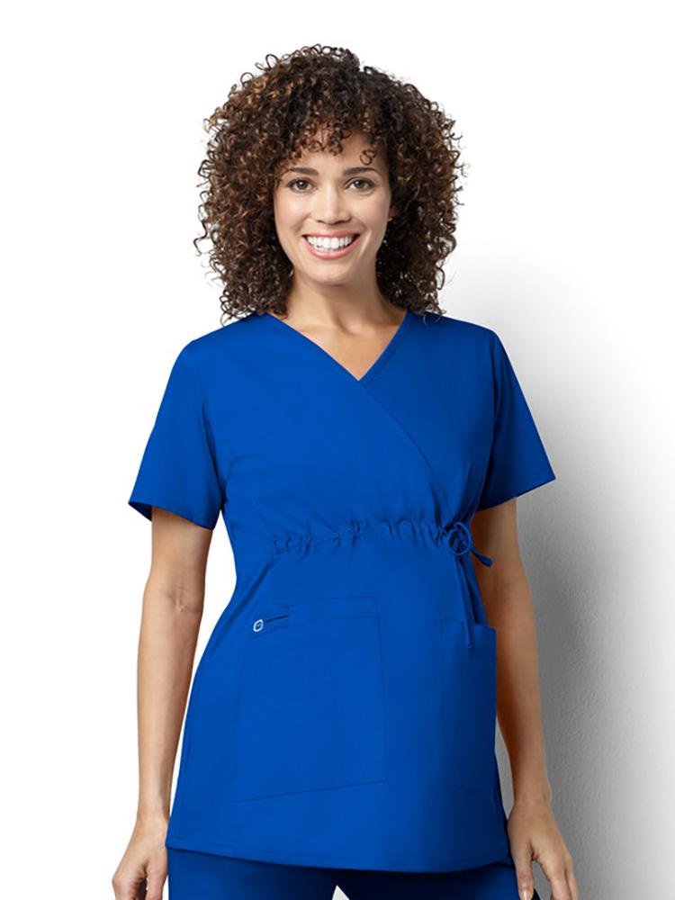 A pregnant Gynecologist wearing a Wonderwink Women's Maternity Mock Wrap Scrub Top in royal size medium featuring stretchy knit side panels.